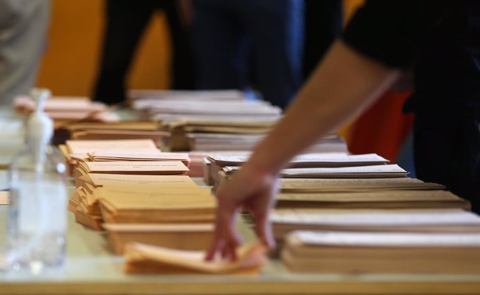 Archivo - Una persona agafa un sobre per votar en un collegi a Madrid