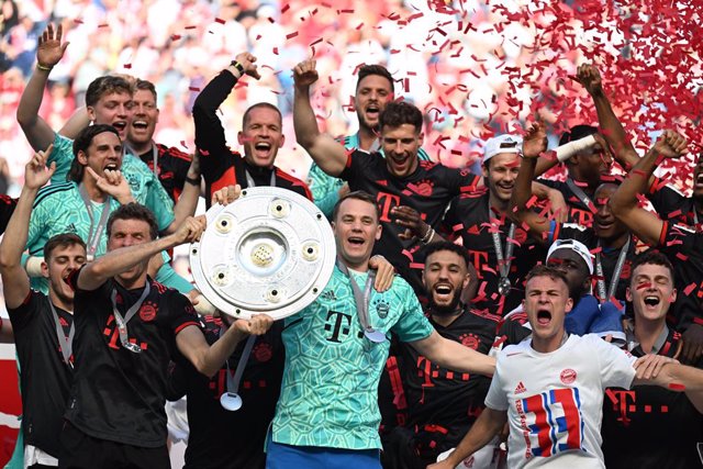 27 May 2023, North Rhine-Westphalia, Cologne: Bayern goalkeeper Manuel Neuer (C) holds the championship trophy while his teammates cheer after winning the 33rd German championship. Photo: Federico Gambarini/dpa - IMPORTANT NOTICE: DFL and DFB regulations 