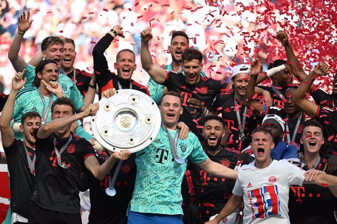 27 May 2023, North Rhine-Westphalia, Cologne: Bayern goalkeeper Manuel Neuer (C) holds the championship trophy while his teammates cheer after winning the 33rd German championship. Photo: Federico Gambarini/dpa - IMPORTANT NOTICE: DFL and DFB regulation