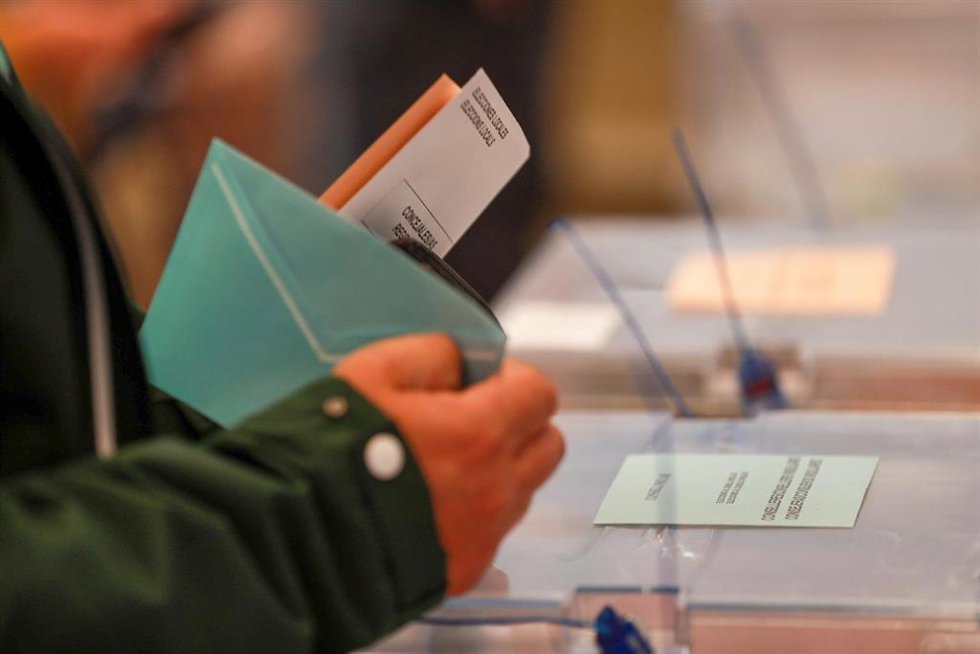 Una persona sostiene papeletas electorales frente a las urnas, a 28 de mayo de 2023,  (España). 