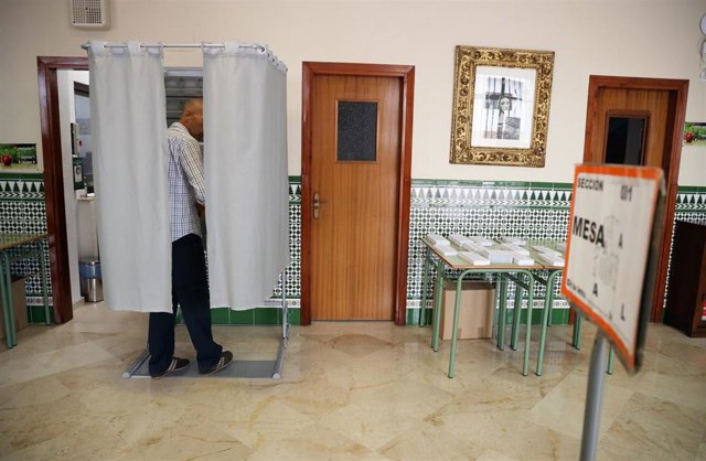 Una persona dentro de una cabina electoral para coger su papeleta para votar, a 28 de mayo de 2023, en Málaga