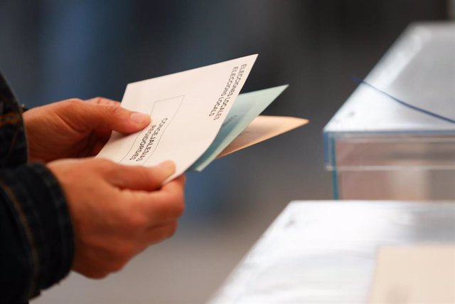 Una persona sostiene papeletas electorales frente a las urnas, a 28 de mayo de 2023, en Palma