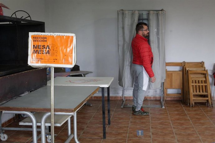 Una persona junto a una cabina electoral 