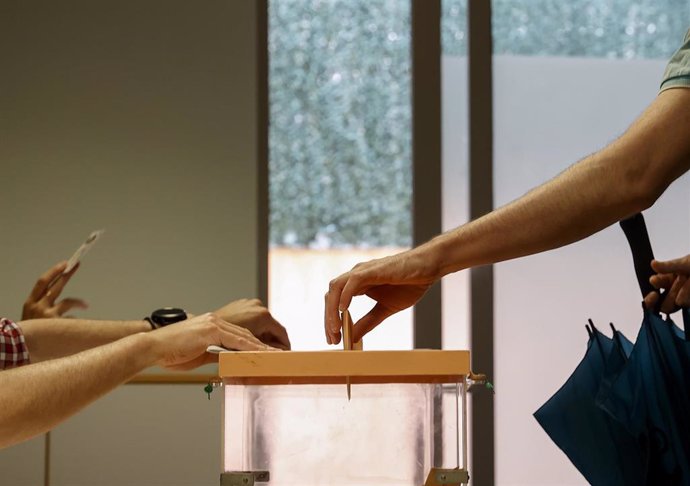 Una persona mete su voto en una urna vota.