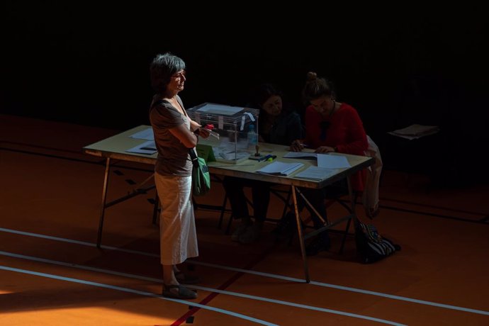 Una dona espera al fet que els membres de la taula electoral comprovin la seva identdad per votar en l'Escola Grvol, a 28 de maig de 2023, a Barcelona, Catalunya (Espanya). Avui, 28M, se celebren eleccions municipals en un total de 8.131 ajuntaments i 