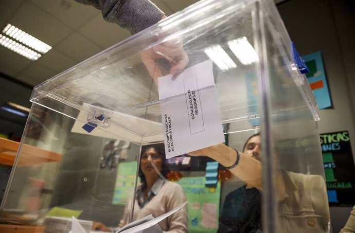 Una persona mete su voto en una urna vota.