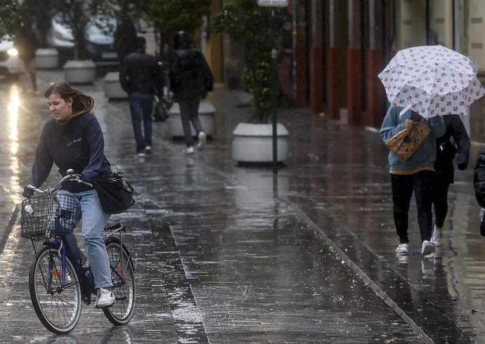 Archivo - Una persona sujeta un paraguas como consecuencia de la lluvia en imagen de archivo