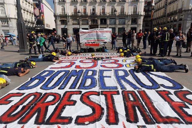 Bomberos se tumban sobre una pancarta que reclama más derechos en una protesta frente a la sede del Gobierno regional en la Puerta del Sol, a 25 de mayo de 2023, en Madrid (España).El comité de huelga de los Bomberos Forestales del Servicio Público de la 