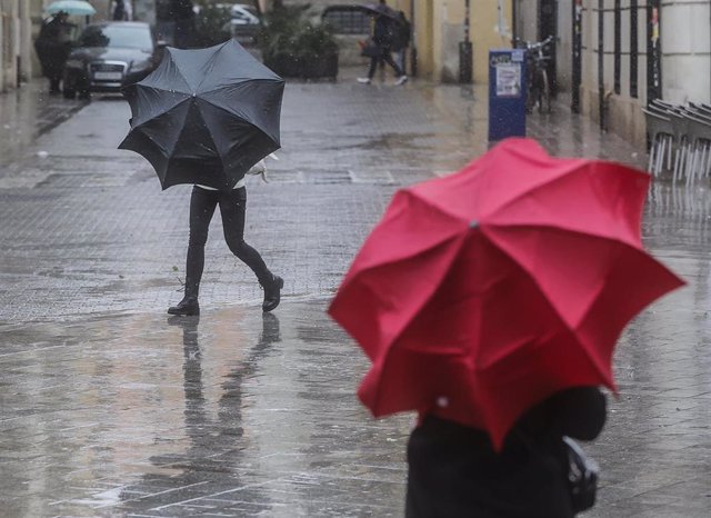 Archivo - Dos personas sostienen paraguas como consecuencia de la lluvia, a 6 de febrero de 2023, en València