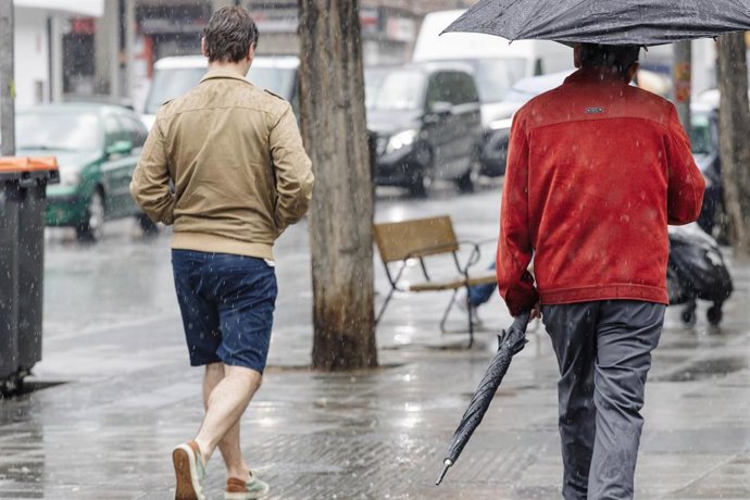 Dos personas pasean bajo la lluvia, a 23 de mayo de 2023, en Madrid (España).