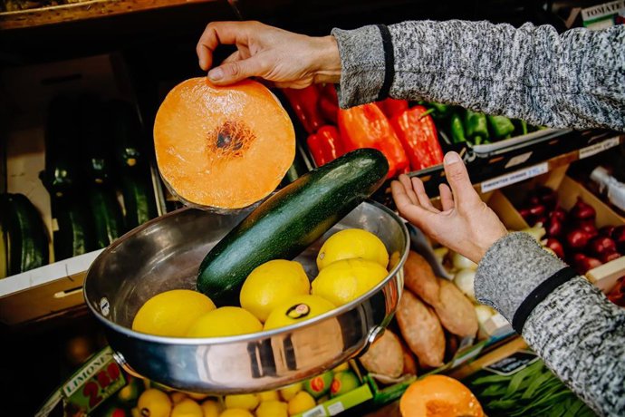 Archivo - Una persona pesa seis piezas de limones, media calabaza y un calabacín en una frutería 
