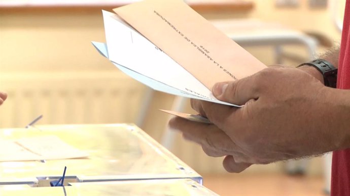 Archivo - Un elector con las papeletas junto a la urna