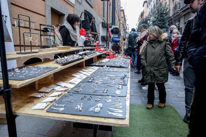 Archivo - Varias personas observan un puesto en el mercado de las Ranas