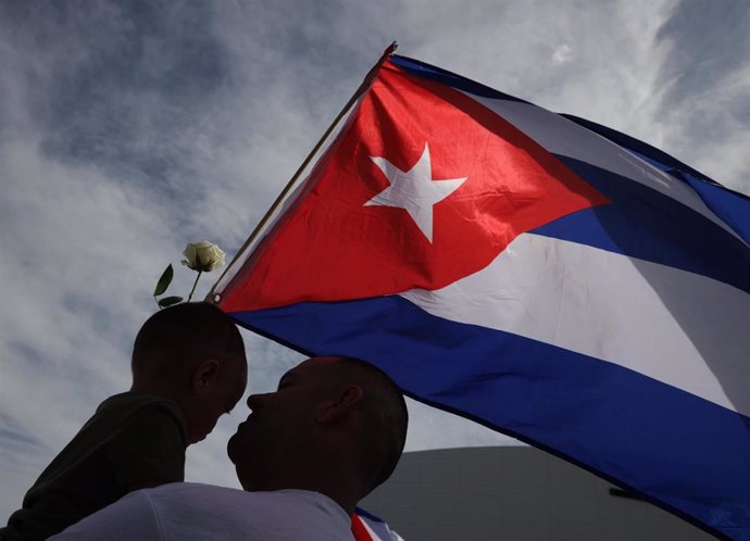 Archivo - Padre e hijo junto a la bandera de Cuba