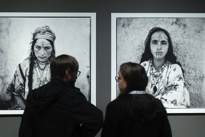 Archivo - Dos personas observan dos fotografías en blanco y negro de la exposición 'Tattoo. Arte bajo la piel' en CaixaForum Valncia (archivo)