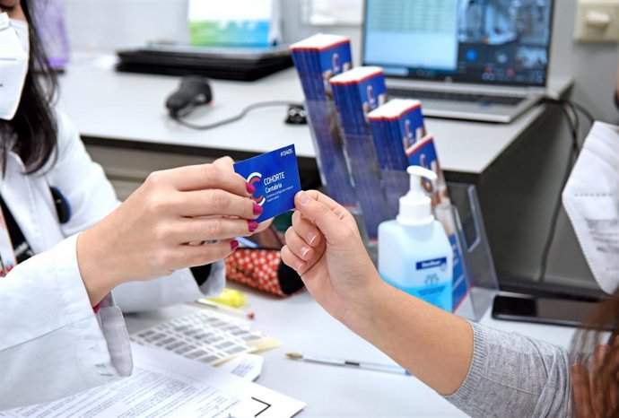 Archivo - Una sanitaria entrega a una voluntaria la tarjeta del proyecto Cohorte Cantabria