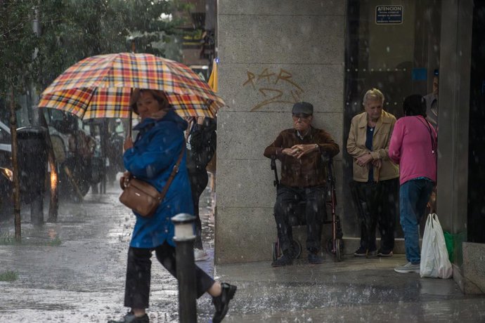 Una mujer con paraguas bajo la lluvia, a 29 de mayo de 2023, en Madrid (España). La Agencia Estatal de Meteorología (Aemet) ha avisado de la alerta naranja en Madrid por la tormenta que ha dejado varias incidencias en la tarde de hoy. 