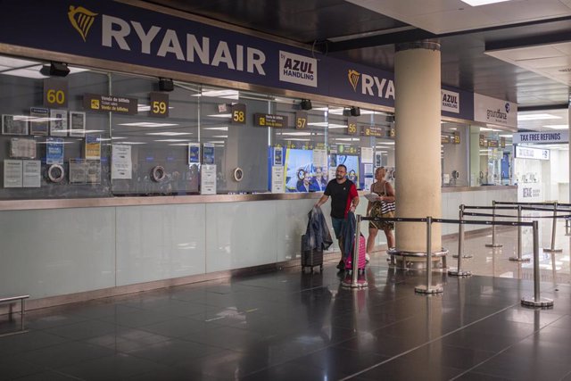 Archivo - Dos personas pasan junto a una ventanilla de Ryanair