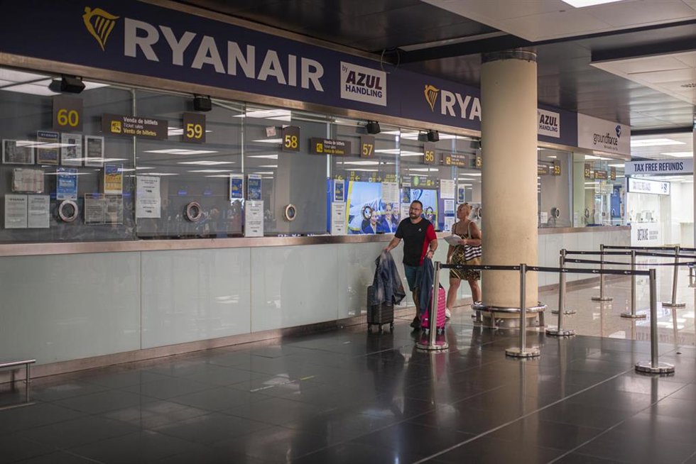Archivo - Dos personas pasan junto a una ventanilla de Ryanair