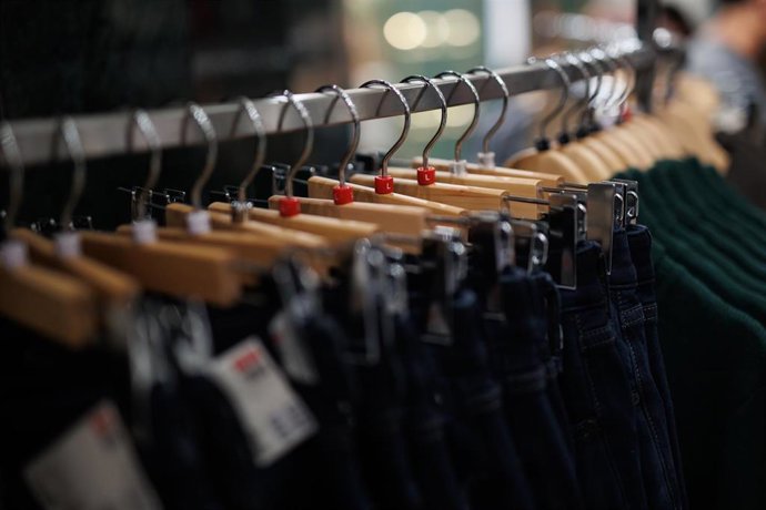 Archivo - Prendas de ropa perchadas en una tienda 