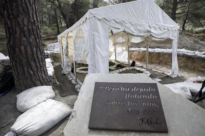Carpa que cubre los trabajos para las exhumaciones en el barranco de Víznar (Granada)  junto a una placa con un poema de Federico García Lorca. Archivo.