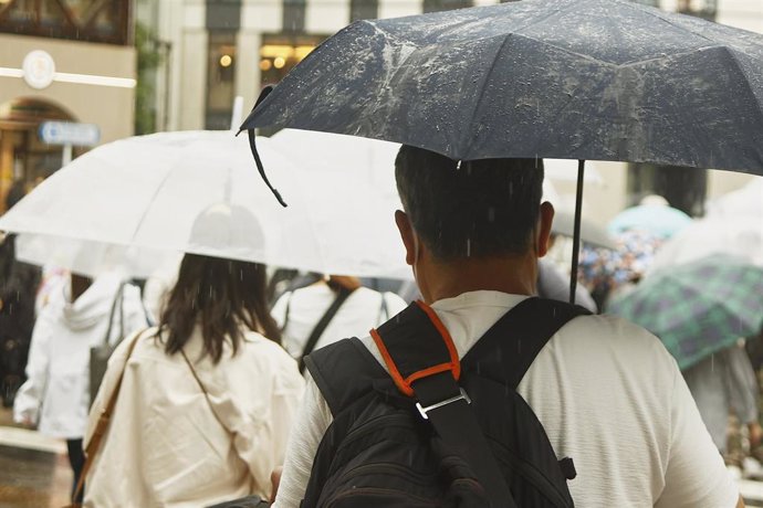 Un grupo de personas resguardándose bajo sus paraguas por las fuertes lluvias en Tokio