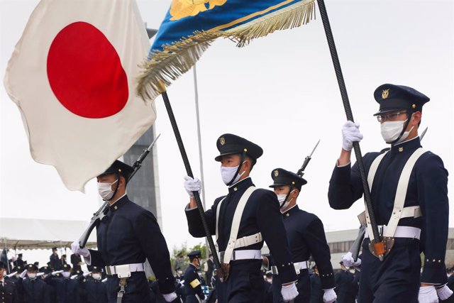 Archivo - April 5, 2021, Yokosuka, Japan: Students of the National Defense Academy hold the Japanese flag together with the flag of the academy during a military parade..Japan's Vice-minister of Defense Yasuhide Nakayama attends the entrance ceremony of t