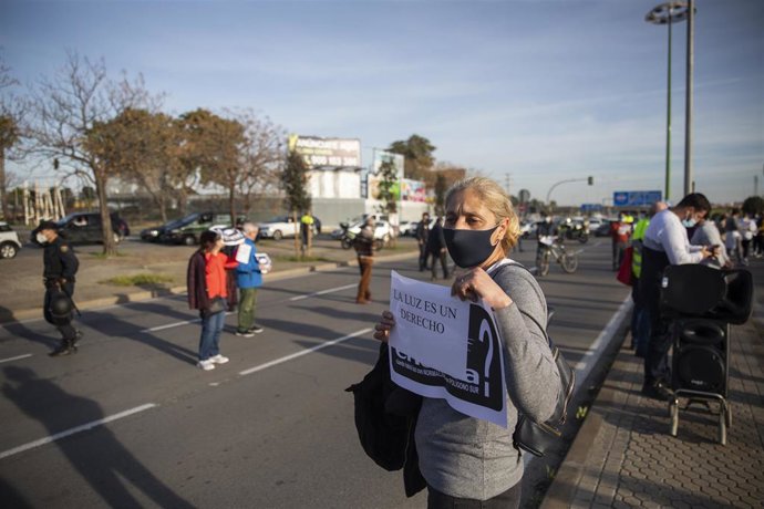 Archivo - Una vecina con un cartel de protesta durante una manifestación promovida en el Polígono Sur por la Plataforma Nosotros También Somos Sevilla por los cortes de luz, en una imagen de archivo.