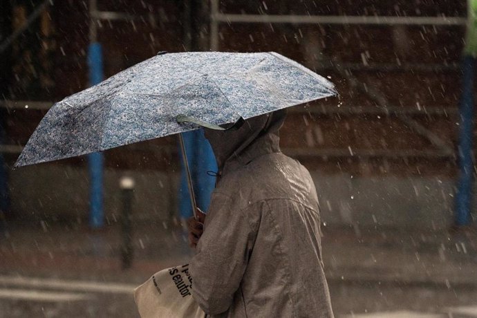 Una mujer con paraguas bajo la lluvia