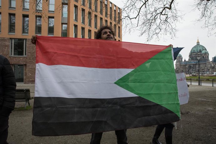 Archivo - Un hombre porta una bandera de Sudán en una protesta en Alemania contra la escalada del conflicto