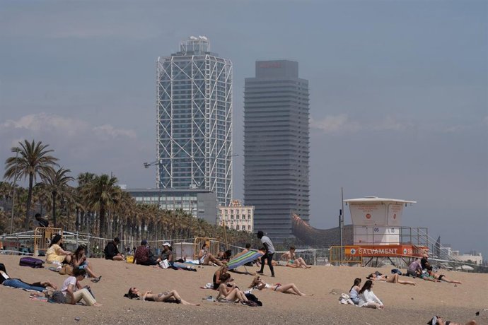 Archivo - Varias personas toman el sol en la playa de la Barceloneta, en Barcelona, Cataluña (España).