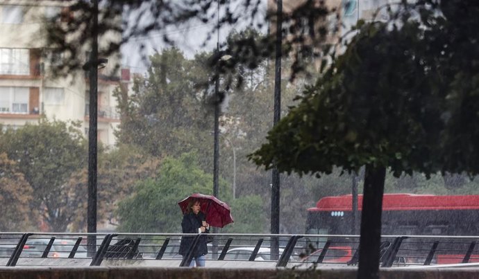 Archivo - Una mujer camina mientras se protege de la lluvia con un paraguas en imagen de archivo