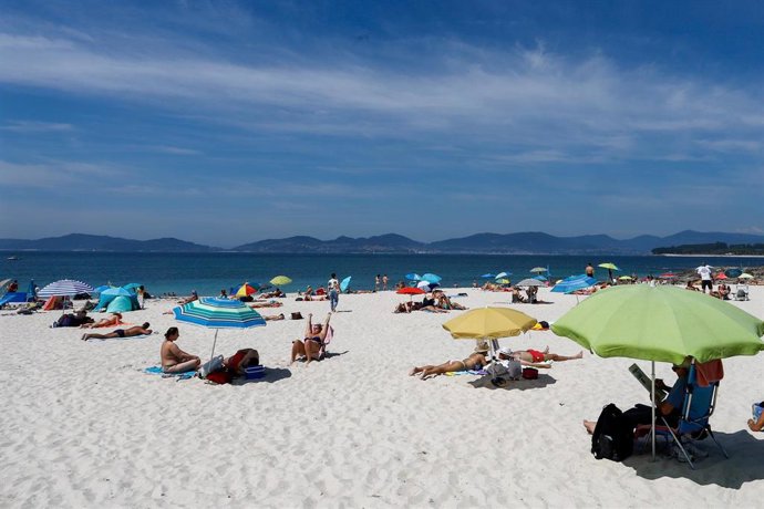 Archivo - Varias personas se bañan y toman el sol en la playa de O Vao, en Vigo