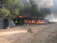 Bomberos trabajan en un incendio declarado en un asentamiento de Lucena (Huelva) que afecta a varias chabolas