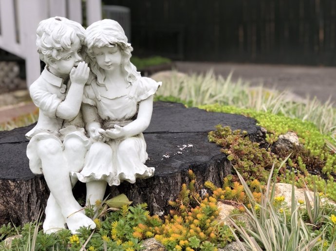 Escultura de dos niños hablando en susurros