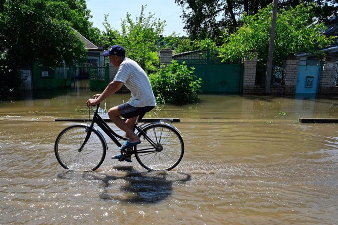 June 9, 2023, Chornobaivka, Ukraine: A local resident rides a bike down a flooded street in the village of Chornobaivka near Kherson. On June 6, the Russian army blew up the dam of the Kakhovka hydroelectric power station, which caused widespread floodi