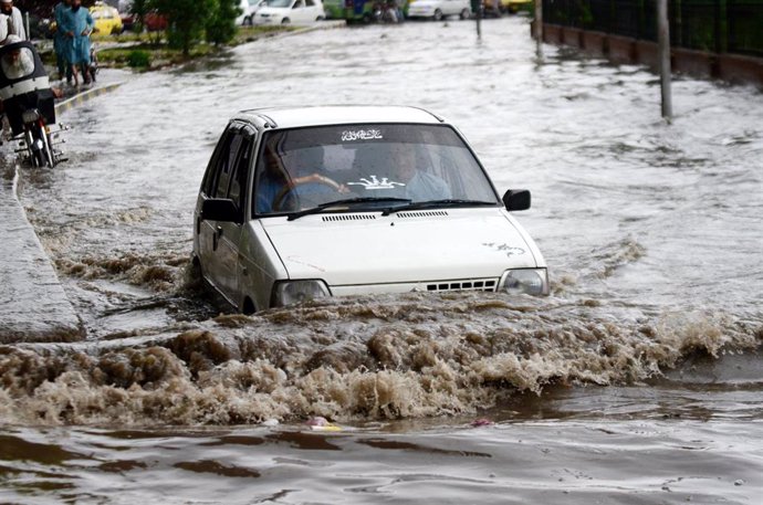 Archivo - Un coche intenta avanzar en una calle inundada en Pakistán