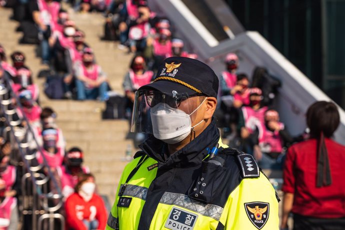 Archivo - November 12, 2020, Seoul, South Korea: A policeman wearing a face mask is seen in front of protesters at Seoul Railway Station during a rally..Korean Railway Workers' Union members stage a rally against KORAIL (Korea Railroad Corporation) and th