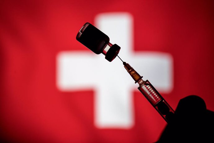 Archivo - January 24, 2021, Poland: In this photo illustration a vial of Pfizer-BioNtech COVID-19 vaccine and a medical syringe displayed over the Switzerland flag.