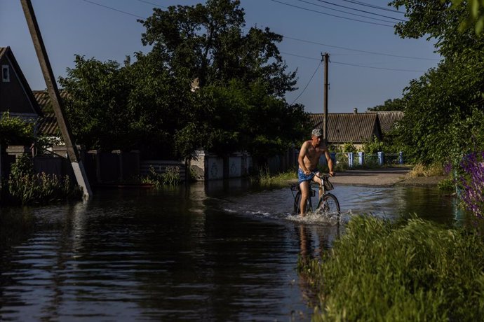 June 9, 2023, Afanasiivka, Mykolaiv Oblast, Ukraine: Security guard Vitali, 33, rides his bicycle through the flood waters after he surveyed the damage to his flooded home at Afanasiivka, Ukraine on June 9, 2023. The region is flooding from the Inhulets