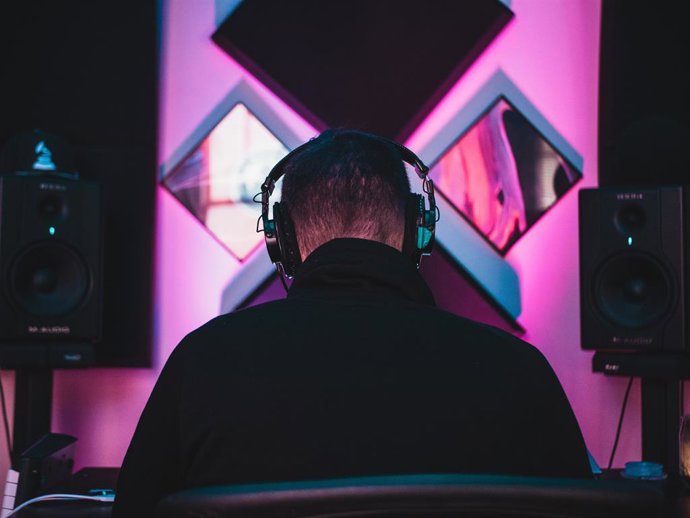 Chico de espaldas con unos auriculares escuchando música