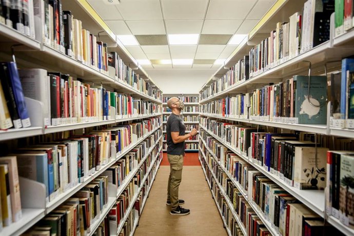 Archivo - Un hombre observa los libros de la biblioteca pública Elena Fortún