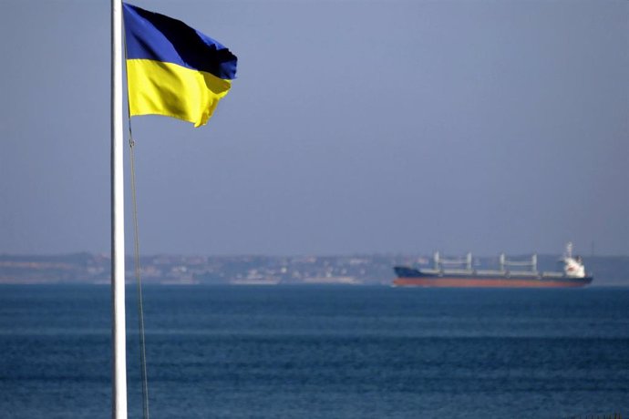 Archivo - Bandera de Ucrania en Odesa frente a un barco cargado de cereales
