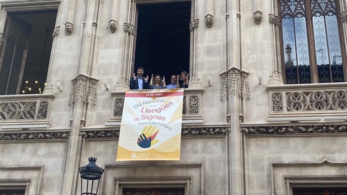 Representantes del Consell de Mallorca colgando una bandera en el Palau del Consell por el Día Nacional de las Lenguas de Signos Catalana y Española
