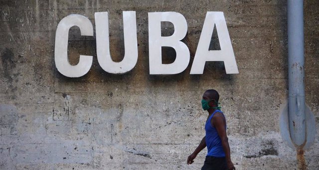 Archivo - Un hombre con mascarilla pase ante un cartel de Cuba