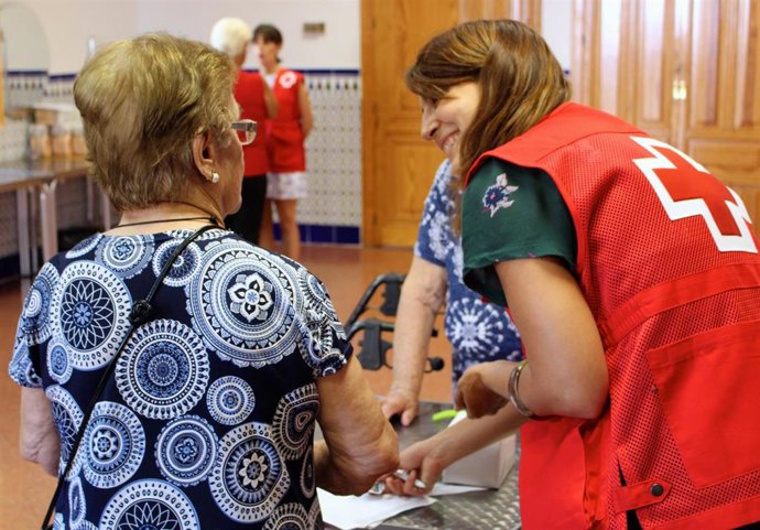 Archivo - Una voluntaria de Cruz Roja con una persona mayor.