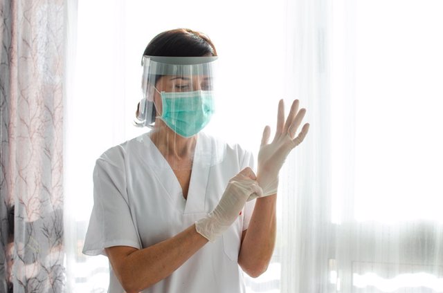 Archivo - Enfermera poniendose los guantes latex.