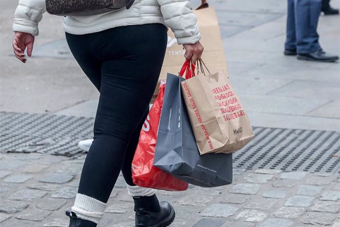 Archivo - Una persona camina con varias bolsas de compras en la calle comercial de Preciados 