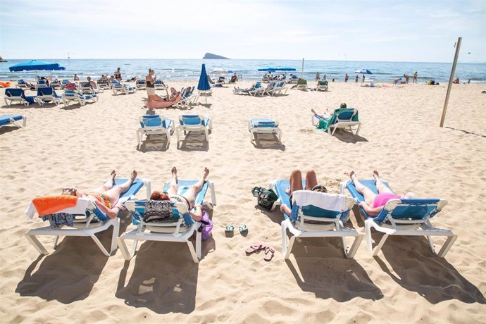 Archivo - Numerosas personas se bañan y toman el sol en la playa 