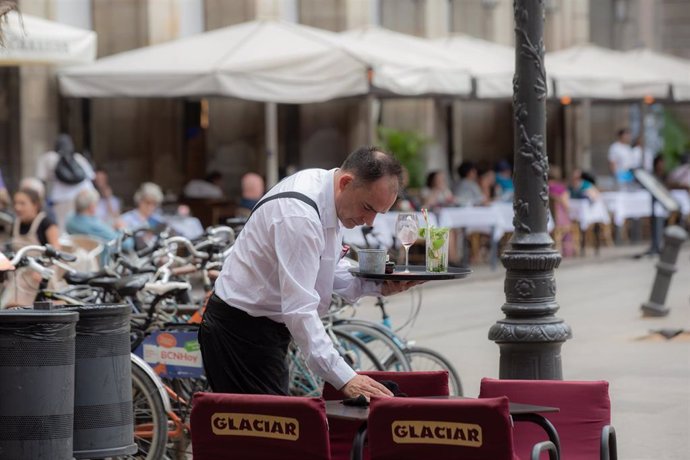 Archivo - Un camarero limpia una mesa en la plaza Real de Barcelona, en Barcelona.